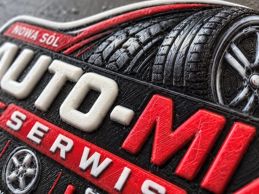Zbliżenie wypukłego reliefu magnesu Auto-Mix – bieżnik opony i litery nazwy warsztatu
